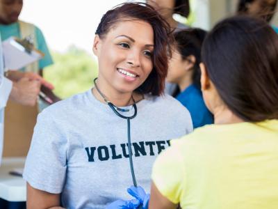 a nurse volunteer smiling at a young girl 